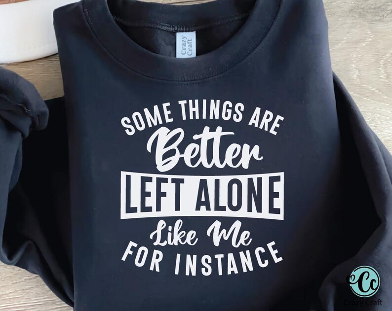 May include: Navy blue sweatshirt with the text "SOME THINGS ARE Better LEFT ALONE Like Me FOR INSTANCE" in white. The sweatshirt has a crew neck and long sleeves. The brand tag "Crazy Craft" is visible.