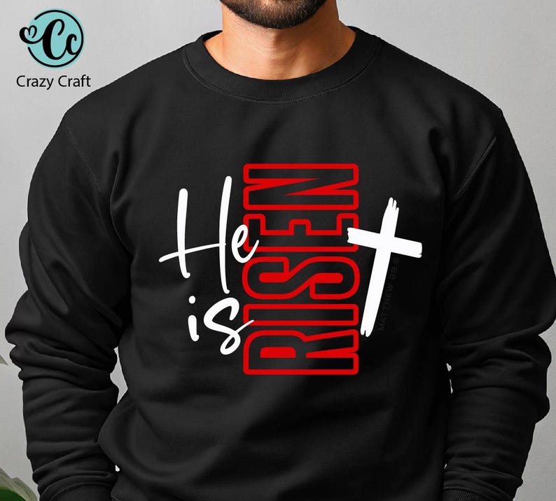 May include: Black sweatshirt with the text "He is Risen" in white and red. The design includes a white cross. The sweatshirt is from Crazy Craft.
