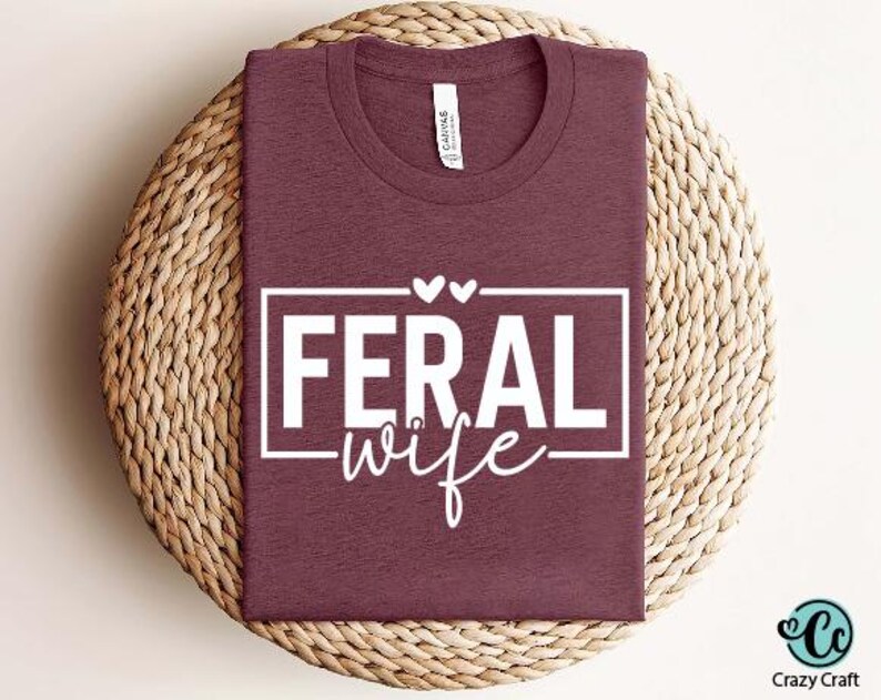 May include: A maroon t-shirt with a white graphic that says "Feral Wife" with two small hearts above the text.