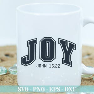 K&ouml;nnte beinhalten: Wei&szlig;e Keramiktasse mit einer schwarzen Grafik des Wortes "JOY" in einer Schriftart im College-Stil. Der Text "JOHN 16:22" ist unter dem Wort "JOY" gedruckt.