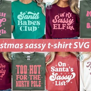 May include: Collection of Christmas-themed t-shirts in various colors, each with a unique, sassy slogan in a retro font. Slogans include "Sleigh Girl Sleigh," "Santa Babes Club," and "In My Sassy Elfera."