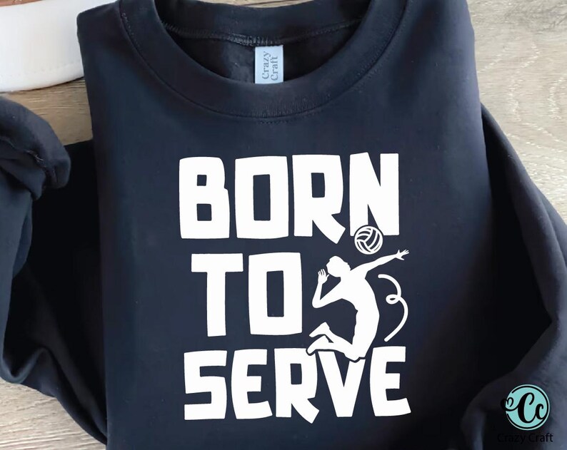 K&ouml;nnte beinhalten: Marineblaues Sweatshirt mit dem wei&szlig;en Schriftzug "BORN TO SERVE". Darunter befindet sich eine wei&szlig;e Silhouette eines Volleyballspielers beim Aufschlag. Das Sweatshirt hat einen Rundhalsausschnitt.