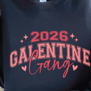 May include: Navy blue sweatshirt with a red and pink graphic. The graphic reads "2026 Galentine Gang" with star and heart accents. The Crazy Craft logo is in the upper right corner.