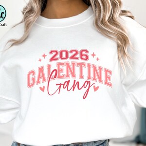 May include: White sweatshirt with a pink and red graphic that reads "2026 Galentine Gang." The design includes hearts and stars. The Crazy Craft logo is in the upper left corner.
