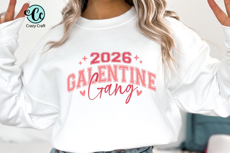 May include: White sweatshirt with a pink and red graphic that reads "2026 Galentine Gang." The design includes hearts and stars. The Crazy Craft logo is in the upper left corner.