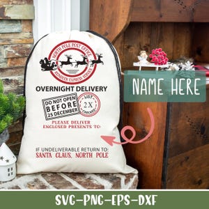 May include: A white canvas Santa sack with black trim and red accents. The sack has a North Pole Post Office logo with reindeer and the text "OVERNIGHT DELIVERY". It also includes the text "DO NOT OPEN BEFORE 25 DECEMBER" and "PLEASE DELIVER ENCLOSED PRESENTS TO:" with a space for a name. The bottom of the sack reads "IF UNDELIVERABLE RETURN TO: SANTA CLAUS, NORTH POLE".