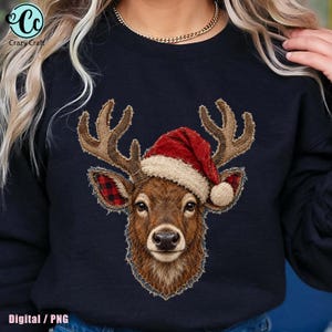 Puede incluir: Una sudadera negra de cuello redondo con un gráfico central de una cabeza de ciervo marrón con un gorro de Papá Noel rojo y blanco. El ciervo tiene astas texturizadas y orejas con estampado de cuadros rojos y negros, estilo aplique.