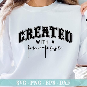 K&ouml;nnte beinhalten: Wei&szlig;er Pullover mit schwarzem Text, der "CREATED WITH A purpose" lautet.