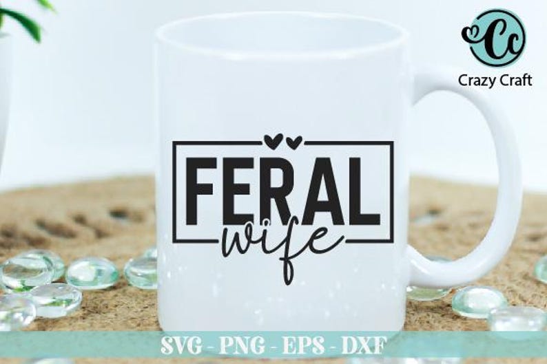 May include: White ceramic mug with a black graphic that says "Feral Wife" in a rectangular frame with two small hearts above the text.