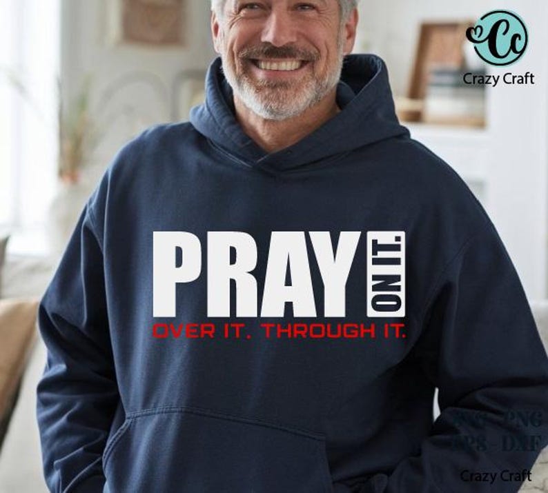 以下が含まれることがあります： 大きな白い文字で「PRAY ON IT」と書かれたネイビーブルーのフード付きスウェットシャツ。その下に、赤で「OVER IT. THROUGH IT.」と書かれています。