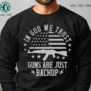 Könnte beinhalten: Schwarzes Sweatshirt mit weißem Grafikdesign. Das Design zeigt eine amerikanische Flagge, ein Gewehr und den Text "IN GOD WE TRUST" und "GUNS ARE JUST BACKUP". Das Crazy Craft-Logo befindet sich oben links.