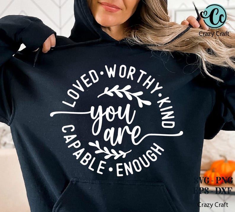 Pu&ograve; includere: Felpa con cappuccio nera con testo bianco che recita "Loved Worthy Kind Capable Enough You Are" con un design floreale.