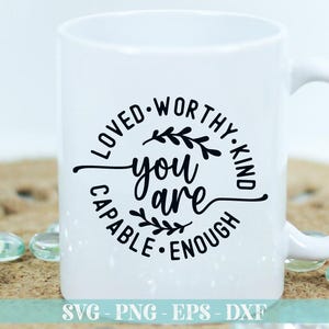 Pu&ograve; includere: Tazza in ceramica bianca con un design circolare nero che dice "Loved Worthy Kind You Are Capable Enough" con un design floreale all'interno del cerchio.