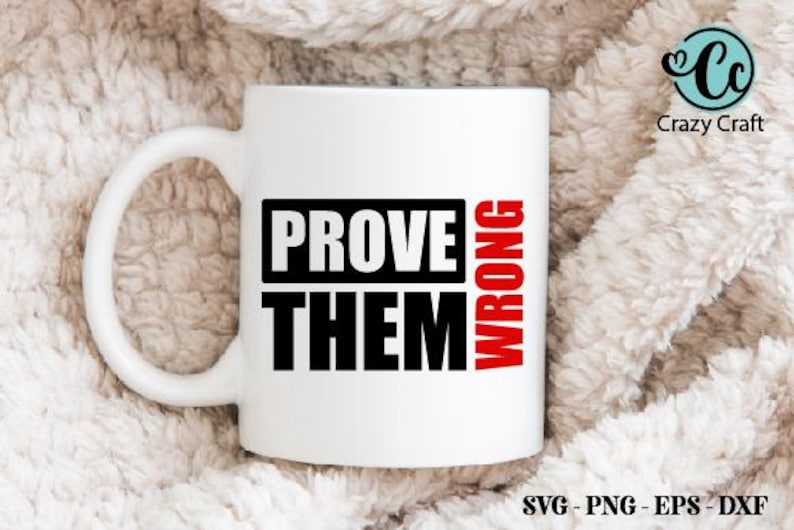 以下が含まれることがあります： 黒と赤で「PROVE THEM WRONG」の文字が入った白いセラミックマグ。マグには大きなハンドルが付いており、柔らかい質感の背景に置かれています。マグはコーヒーや紅茶の標準サイズです。