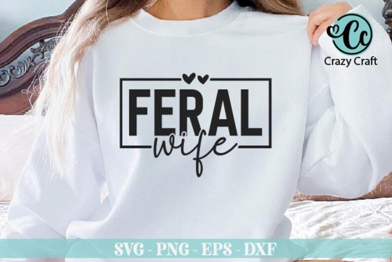 May include: White sweatshirt with black text that reads "FERAL wife" in a box with two hearts above the text.