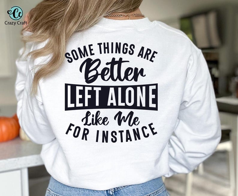 May include: White sweatshirt with the text "SOME THINGS ARE Better LEFT ALONE Like Me FOR INSTANCE" in black. The Crazy Craft logo is in the upper left corner. The sweatshirt is being worn.