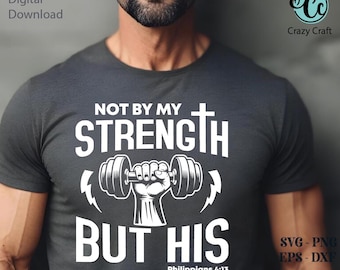 May include: Dark gray t-shirt with white text and graphics. The shirt features the words "NOT BY MY STRENGTH BUT HIS" with a dumbbell and cross design. The text "Philippians 4:13" is also included. The Crazy Craft logo is visible.