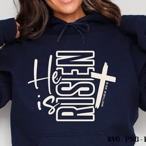 May include: Navy blue hoodie with the words "He is Risen" in white, along with a white cross and the text "Matthew 28:6." The hoodie also has the Crazy Craft logo and SVG, PNG, EPS, and DXF file type information.