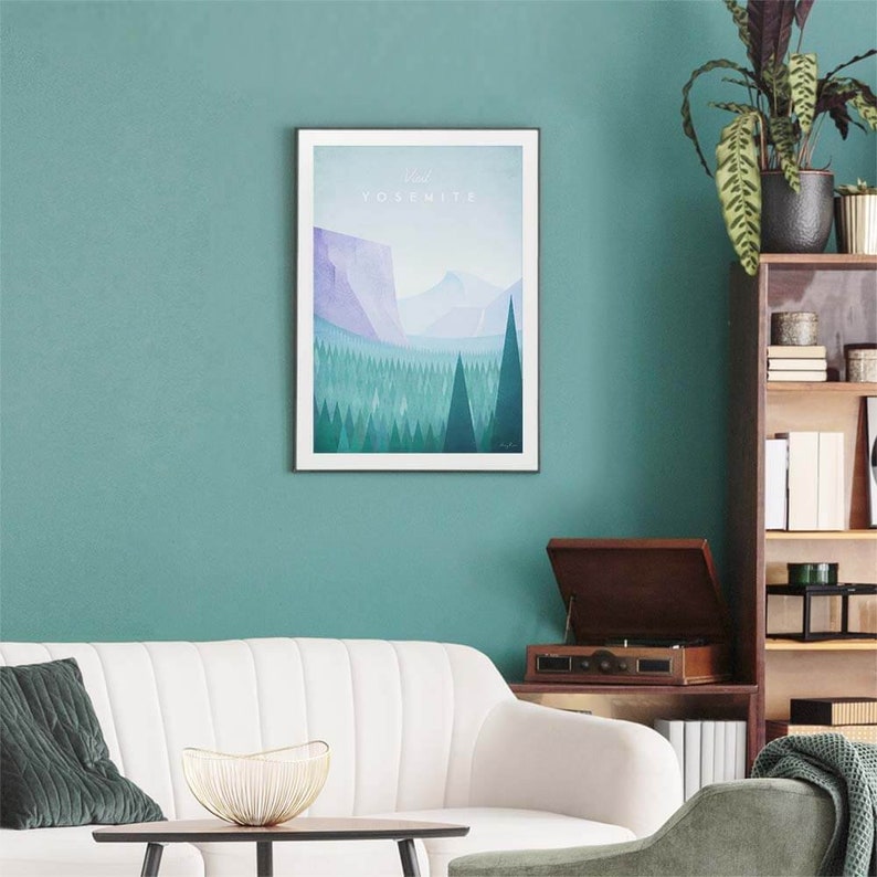 Puede incluir: Una impresi&oacute;n enmarcada de un paisaje estilizado con una cordillera y un bosque en tonos azules y verdes. El texto "Yosemite" est&aacute; impreso en blanco en la parte superior de la impresi&oacute;n.
