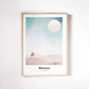 Könnte beinhalten: Eine Aquarell-Illustration eines Kamels mit einem Reiter in der Sahara. Der Himmel ist hellblau mit einer großen weißen Sonne. Der Text "Marokko" und "Sahara-Wüste" befindet sich am unteren Rand des Bildes.