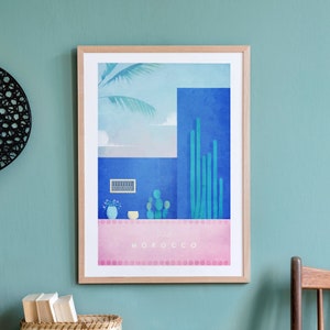 May include: A framed print with a blue and green illustration of a building with a palm tree and cacti. The print has the text "Visit Morocco" at the bottom.