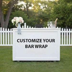 May include: A white bar wrap with the text "CUSTOMIZE YOUR BAR WRAP" in black. The bar is set up outdoors on a green lawn, with a white picket fence in the background. A bouquet of flowers and champagne are on top.