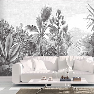 May include: Black and white illustration of tropical plants, including palm trees, ferns, and other foliage. The illustration is printed on a white background and is framed by a white couch and a coffee table.
