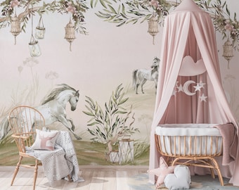 May include: A pink canopy crib with a white cloud mobile hanging above it. The crib is in a room with a pink and green floral wallpaper featuring two white horses and a wooden chair with a white blanket.