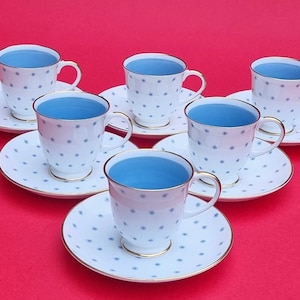 May include: Set of six white teacups and saucers with a blue and white star pattern. The cups and saucers have a gold trim.