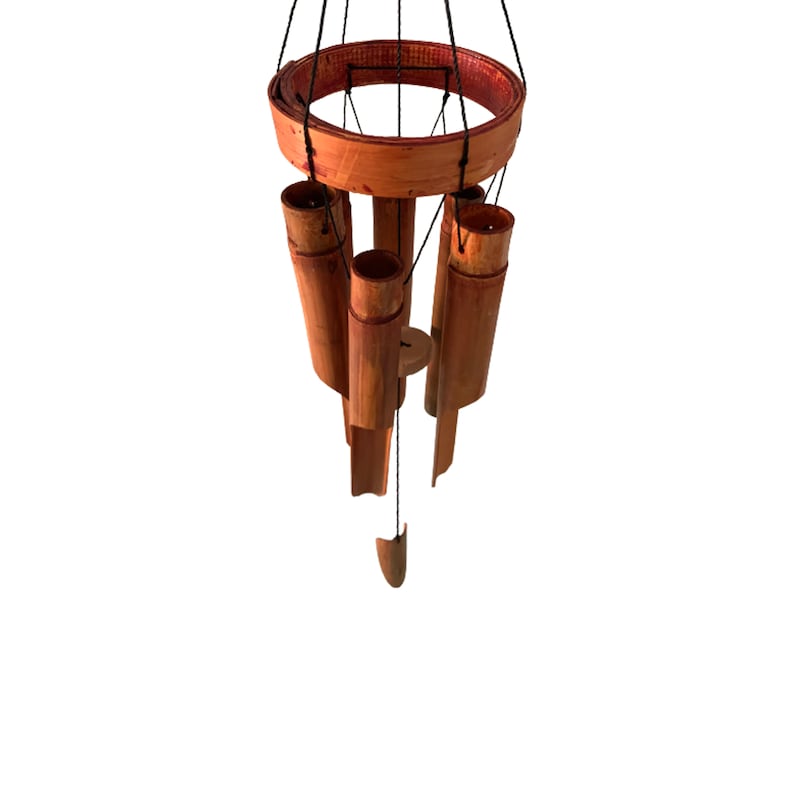May include: A wooden wind chime with a circular top and five hanging tubes. The tubes are made of natural bamboo and are stained a reddish brown color. The wind chime is suspended from a black string.