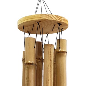 Puede incluir: Un carill&oacute;n de viento de madera con varios tubos de bamb&uacute; colgando de una parte superior circular de madera. Los tubos est&aacute;n atados con cuerda negra.