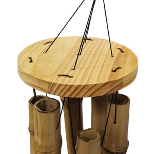 Puede incluir: Un carill&oacute;n de viento de madera con varios tubos de bamb&uacute; colgando de una parte superior circular de madera. Los tubos est&aacute;n suspendidos por cuerdas negras.