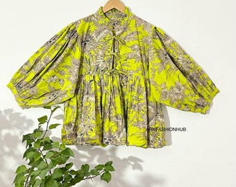 May include: A lime green blouse with a floral pattern in shades of gray and beige. The blouse has a high neckline, a tie closure, and voluminous, elbow-length sleeves. The text "RKFASHIONHUB" is visible on the right side.