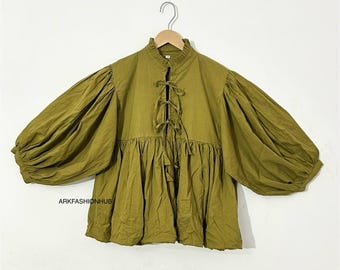 May include: Olive green blouse with a high, ruffled collar and long, voluminous sleeves. The front features a lace-up detail. The blouse is hanging on a wooden hanger. The text "ARKFASHIONHUB" is visible on the bottom of the blouse.