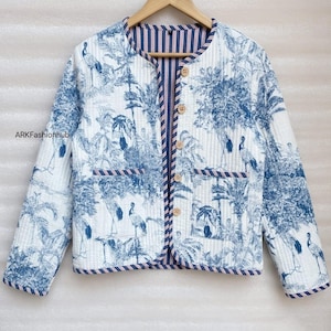 Op de afbeelding: Een doorgestikt jack met een blauw-witte toile-print met kraanvogels en palmbomen. Het jack heeft een ronde halslijn, lange mouwen, twee voorzakken en vijf lichtbruine knopen. De binnenvoering is voorzien van blauw-witte strepen.