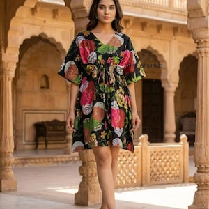May include: A black kaftan dress with a floral print, V-neck, and drawstring waist. The dress has a vibrant pattern of pink, red, and orange flowers and foliage. The text "ARKfashionhub" is visible. The model wears gold heels.