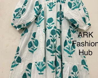 Può includere: Abito bianco a balze con stampa floreale turchese e maniche lunghe a sbuffo. L'abito ha un colletto alla coreana e uno scollo a goccia. Il testo "ARK Fashion Hub" è visibile in basso a destra.