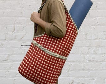 May include: A red and white gingham patterned yoga mat bag with a long shoulder strap and a zippered front pocket. The bag contains a rolled blue yoga mat. The text ARKFashionhub is printed in black on the front of the bag.
