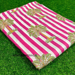 Puede incluir: Tela doblada con un patrón de rayas rosas y blancas. La tela presenta un diseño repetido de palmeras verdes y amarillas. El texto "ARKAFASHIONHUB" es visible en la esquina inferior izquierda.