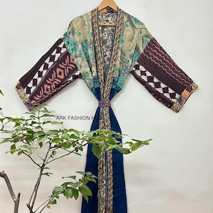 May include: A patterned kimono robe with a mix of colors including brown, teal, and beige. The robe has long sleeves with geometric designs and a dark blue sash. The text "ARK FASHION H" is visible on the image.