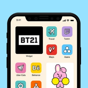 May include: A screenshot of an iPhone displaying a variety of app icons, including Uber Eats, Behance, Asana, Twitch, and Maps. The app icons are arranged in a grid pattern on a beige background. The top left corner of the screen displays a black square with the text "BT21" in white. The bottom right corner of the screen displays a pink cartoon rabbit with yellow pom-poms.