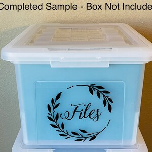 Puede incluir: Una caja de almacenamiento de pl&aacute;stico transparente con un interior azul claro. La caja tiene una pegatina de vinilo negro con una corona y la palabra "Archivos" en letra cursiva.