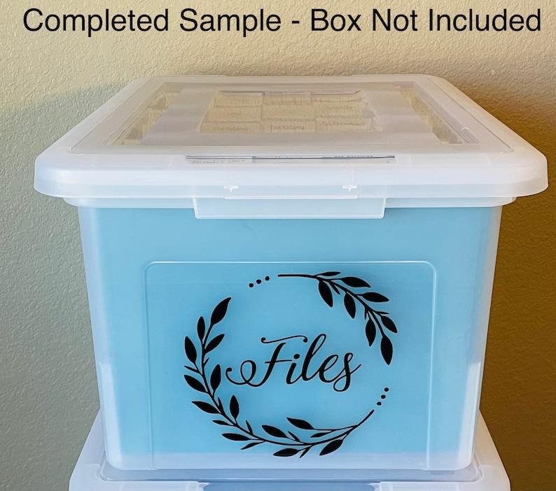 Puede incluir: Una caja de almacenamiento de pl&aacute;stico transparente con un interior azul claro. La caja tiene una pegatina de vinilo negro con una corona y la palabra "Archivos" en letra cursiva.