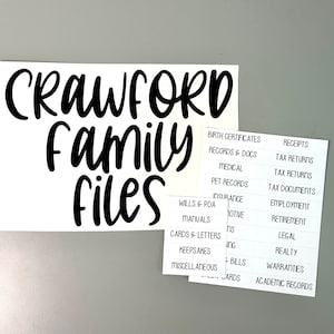 May include: White labels with black text for organizing family files. The labels read "Crawford Family Files" and include categories such as "Birth Certificates", "Records & Docs", "Medical", "Pet Records", "Wills & POA", "Insurance", "Manuals", "Cards & Letters", "Keepsakes", "Miscellaneous", "Receipts", "Tax Returns", "Tax Documents", "Employment", "Retirement", "Legal", "Realty", "Warranties", and "Academic Records".