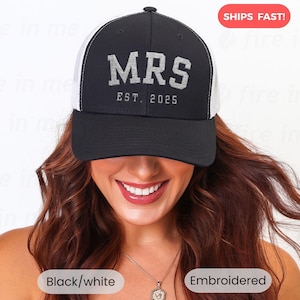 May include: A black and white trucker cap featuring the embroidered text "MRS EST. 2025". The front panel is black, and the back is white mesh. The words "Black/white" and "Embroidered" are also visible on the image.