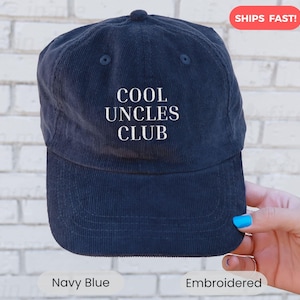 May include: Navy blue corduroy baseball cap with the text "COOL UNCLES CLUB" embroidered in white. The hat has a curved brim and a top button. A stylish accessory for any uncle.
