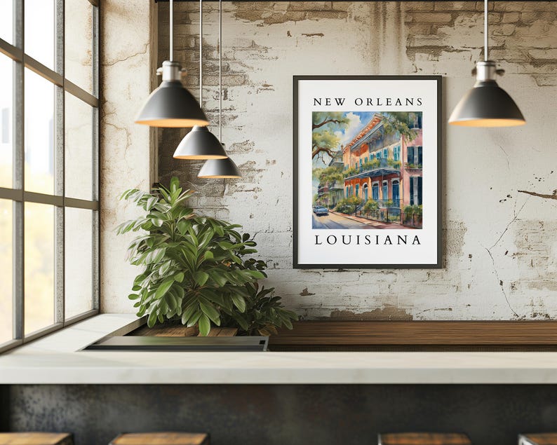 May include: A framed watercolor painting of a street scene in New Orleans, Louisiana. The painting depicts colorful buildings with balconies and lush greenery. The text "NEW ORLEANS" and "LOUISIANA" is printed below the image.