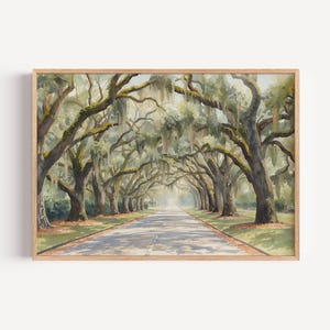 Puede incluir: Impresión enmarcada de acuarela de una avenida arbolada. La imagen muestra una larga carretera flanqueada por grandes árboles con musgo colgante. La obra de arte está enmarcada en un marco de madera, con una paleta de colores suave y natural.