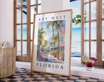 May include: A framed watercolor painting of a street scene in Key West, Florida. The painting depicts colorful buildings, palm trees, and a car driving down the street. The text "KEY WEST FLORIDA" is printed below the image.