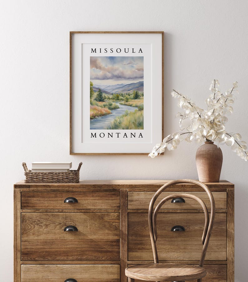 May include: A framed watercolor painting of a river winding through a valley with mountains in the background. The painting is titled "Missoula, Montana".